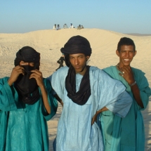 Young men standing in the dunes of Essakane, in the Sahara desert.